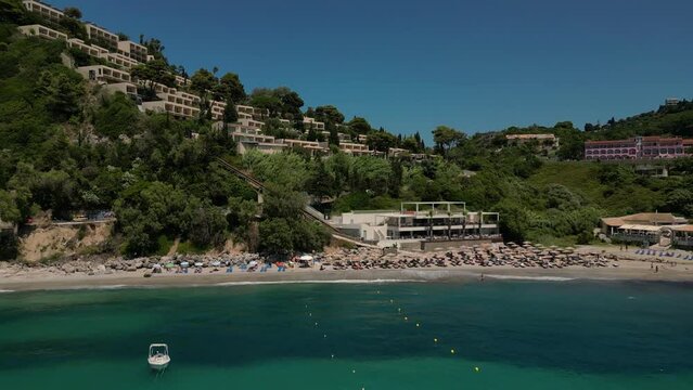 Drone footage of boats gently swaying in the sunny sea, moored not far from the Paralia Ermones Beach, on a hot day