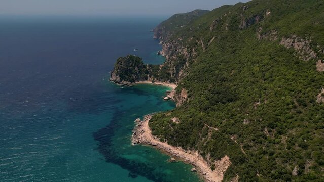 Drone footage of boats gently swaying in the sunny sea, moored not far from the Paralia Ermones Beach, on a hot day
