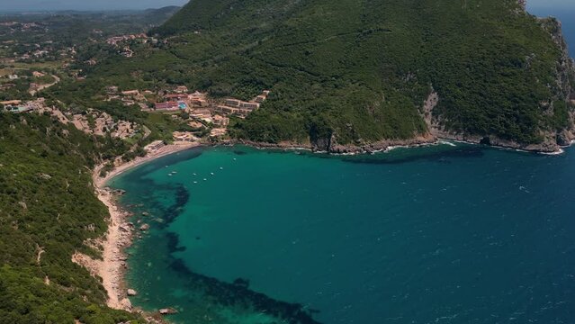 Drone footage of boats gently swaying in the sunny sea, moored not far from the Paralia Ermones Beach, on a hot day