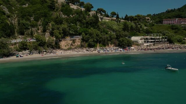 Drone footage of boats gently swaying in the sunny sea, moored not far from the Paralia Ermones Beach, on a hot day