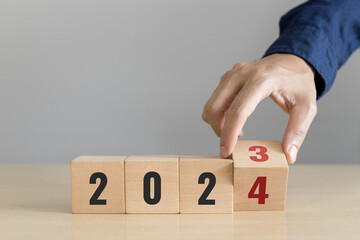 Hand flip wooden cube with the number 2023 to 2024. Start concept. Happy new year 2024