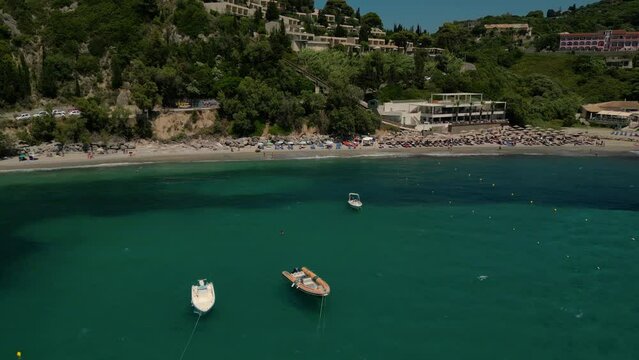 Drone footage of boats gently swaying in the sunny sea, moored not far from the Paralia Ermones Beach, on a hot day