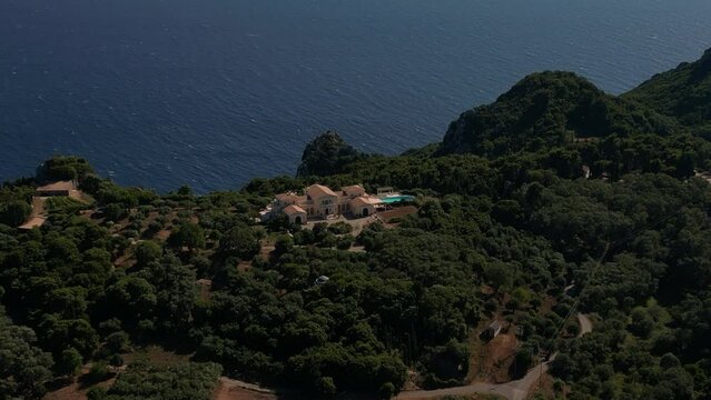 Beautiful mansion located atop a forested mountain on Corfu Island with the blue sea in the background