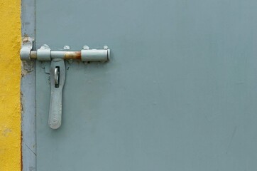 A metal door handle with a locker on gray painted metal wall background.