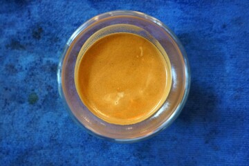A top view of a espresso in a glass on a blue background, life style concept.