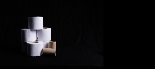 Toilet paper to go to the bathroom in a column with worn paper rolls and on a black background....