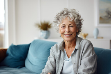 Fototapeta na wymiar Happy pretty senior woman sitting on couch at cozy home, looking at camera with toothy smile. Positive blonde older lady enjoying leisure on comfortable sofa, posing for indoor portrait. Generative AI