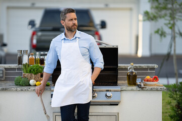 cook man at bbq and grill outdoor, copy space. photo of cook man at bbq and grill in apron.