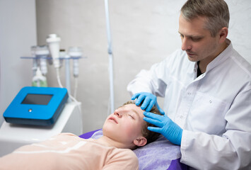 a cosmetologist doctor makes cosmetic procedures on the face of a young guy in a beauty salon