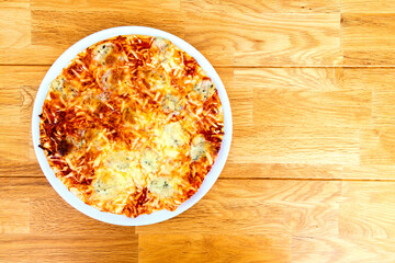 Pizza Margherita on a plate on wooden table, top view