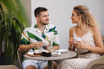 Happy couple of man and woman sitting in cafe and drink coffee