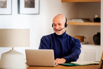 Male customer service assistant business man wearing headset and using laptop for work - 634448923