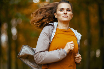 stylish woman in fitness clothes in park jogging