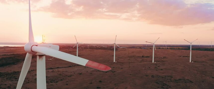 Scenic Aerial view of wind turbines farm in sunset time. Anamorphic 2.39 scope footage with lens flares