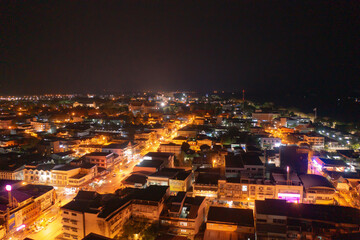Fototapeta premium Aerial view of residential neighborhood roofs. Urban housing development from above. Top view. Real estate in Nakhon Phanom province city, Thailand. Property real estate at night.