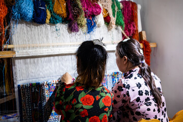 Woman is weaving beautiful carpet with Uzbekistan silk