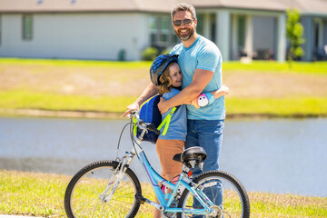 fathers parenting with son outdoor. childhood of son supported by fathers care. father hug son on bicycle at fathers day. active father setting a example for fathers son. family relationship