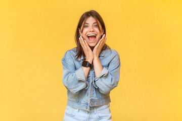 Portrait of excited amazed woman wearing denim jacket screaming with excitement, being in very good...