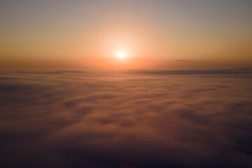 Aerial view from above at high altitude of dense puffy cumulus clouds flying in evening. Amazing...