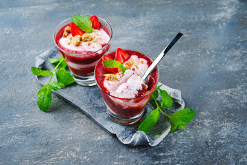 Traditionelle gefrorene Erdbeersuppe mit Erdbeereis und Crumbles serviert als Nahaufnahme auf einem grauen Stein Design Tablett mit Textfreiraum