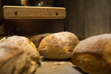 Homemade baked bread buns and a rustic dough scraper. Cooking home concept.