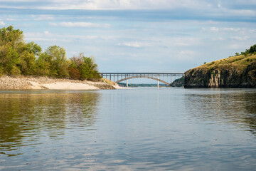 Arched bridge between high rocky banks of a wide river