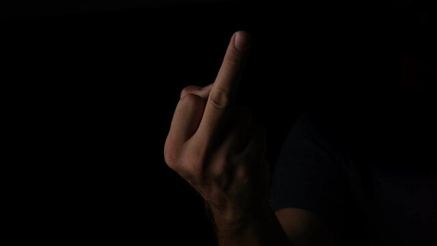 A hand shown in slow motion against a black background, giving the middle finger to the camera