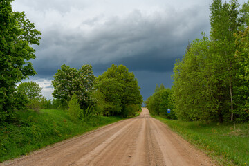 Fototapeta na wymiar A gravel road on a beautiful summer day against the background of a rainy sky