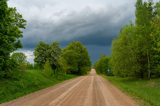 A gravel road on a beautiful summer day against the background of a rainy sky