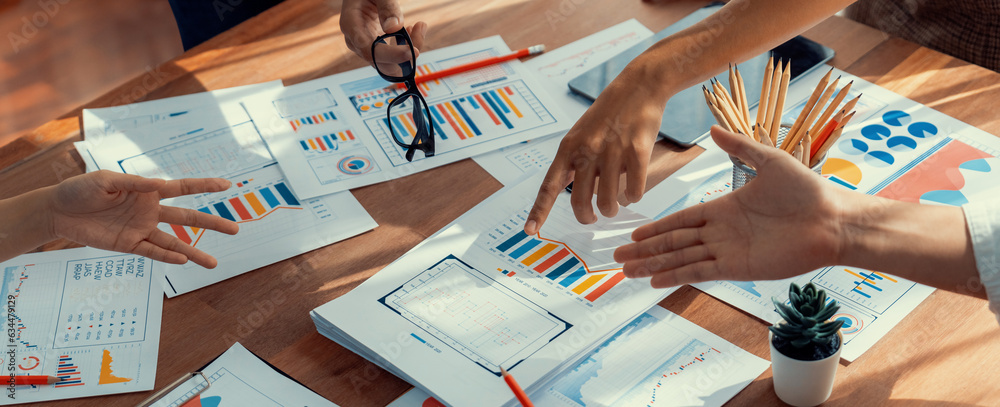 Leinwandbilder Analyst team utilizing BI Fintech to analyze and pointing at financial dashboard paper office. Businesspeople examining report paper on table for business insight. Panorama shot. Scrutinize