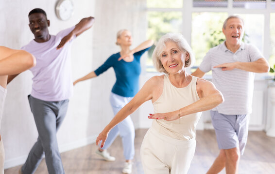 Clients of fitness studio are elderly lady and people of different ages actively moving, doing aerobics or modern types of dancing. Good physical shape, healthy lifestyle