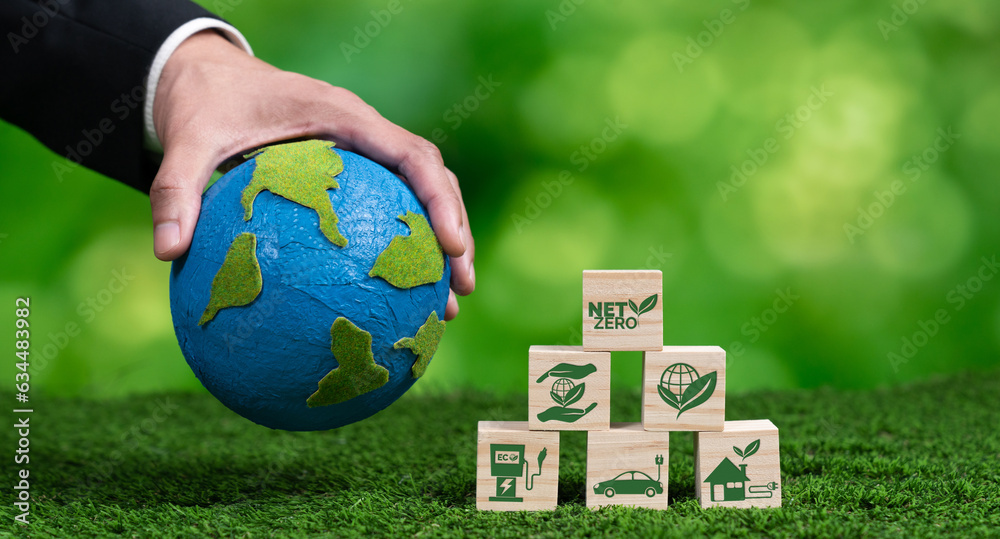 Wall mural businessman hand with paper globe and net zero symbol cube for eco awareness. ethical company reduce