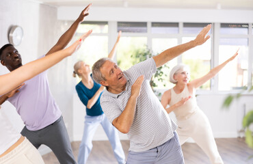 Senior europian man and friends people of different ages dancing in studio or gym doing sports or...