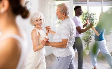 Group of multinational sports aged people rehearsing social dance in dance hall