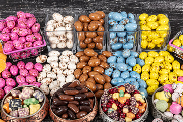 Heap of sugared almonds and hazelnuts dragees in chocolate isolated on dark background. Handmade colorful chocolate candies filled with nuts. Chocolate candies and Pebblestone chocolate dragees.