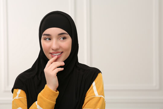 Beautiful Muslim woman wearing black hijab indoors