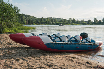 inflatable raft-catamaran for whitewater sports is moored on the river bank