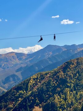 Silhouette of two people zip lining in mountains, Wasatch front, Sundance, Utah, USA