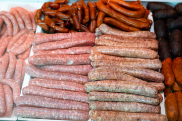 Different types of meat sausages laid out on counter in butcher shop..
