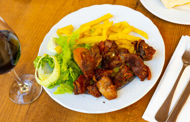 Appetizing grilled pork spare meal with garnish of french fries and leaf salad