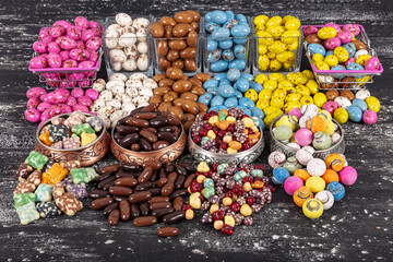 Heap of sugared almonds and hazelnuts dragees in chocolate isolated on dark background. Handmade colorful chocolate candies filled with nuts. Chocolate candies and Pebblestone chocolate dragees.