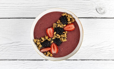 Smoothie bowl with strawberries, blackberries and granola on a white background. Healthy breakfast. Top view