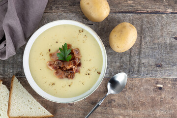Creamy potato soup with bacon, croutons, ingredients on a wooden background. Top view. Copy space. French vichyssoise soup.