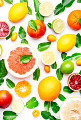 Colorful citrus fruits, food background, top view. Mix of different  fruits: orange, grapefruit, lemon, lime and other with leaves on white table, top view