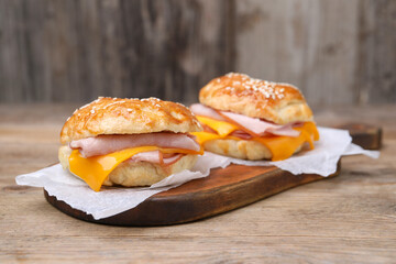 Delicious bagels with ham and cheese on wooden table. Space for text