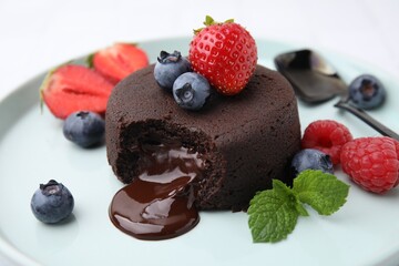 Delicious chocolate fondant, berries and mint on plate, closeup
