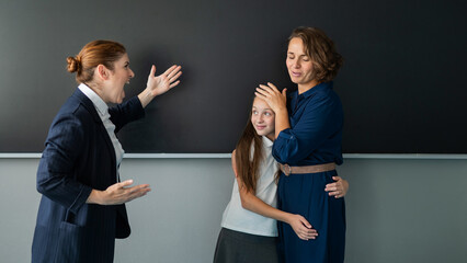 The teacher screams at the schoolgirl and her mother standing at the blackboard. 