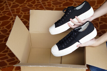 Close up customer holds new shoes from cardboard box from shopping. Concept, footwears , Checking...