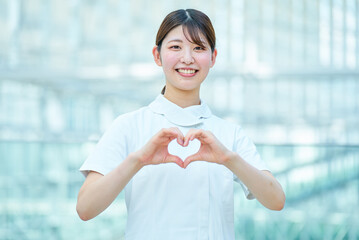 両手でハートの形を作る白衣の女性