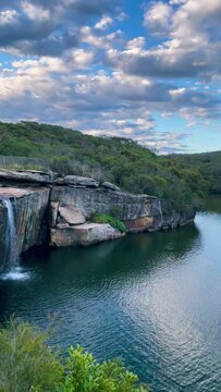 4k Video -Panning views from above at sunset from the top of the waterfall over the lagoon and the ocean further away at Wattamolla Beach in Royal National Park, NSW, Australia.